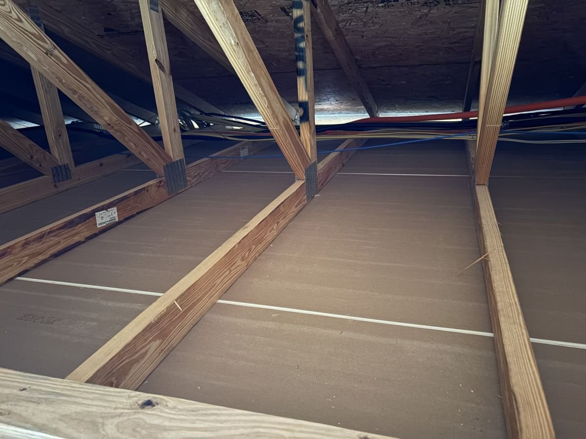 Un-insulated attic with exposed rafters and joists before blown-in insulation installation.