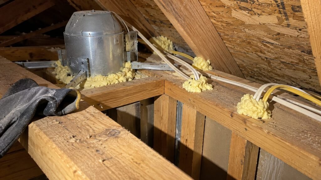 Spray foam sealing gaps around wires in a Florida attic before new insulation